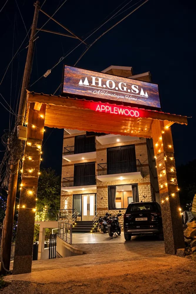 Illuminated entrance of HOGS Panorama in Manali at night, with warm fairy lights and a wooden archway