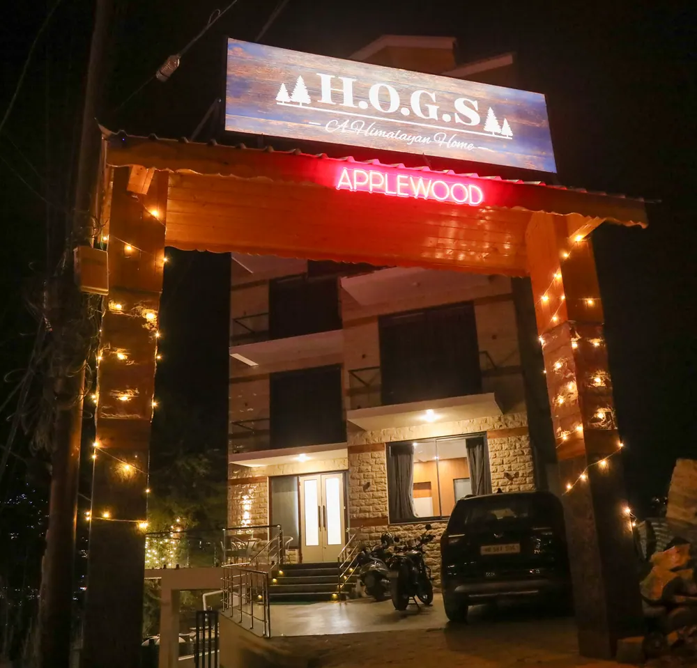 Entrance arch at night with an illuminated H.O.G.S sign and warm string lights along the wooden posts