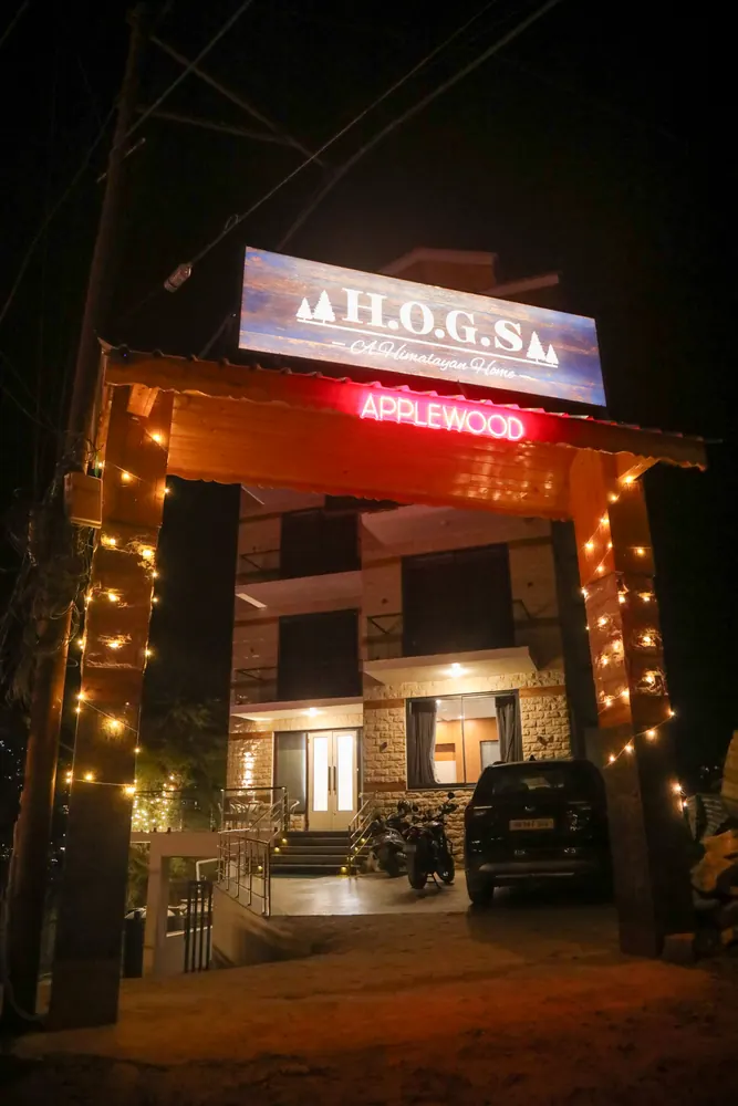 Night view of the entrance with an illuminated H.O.G.S sign, string lights and the stone building behind