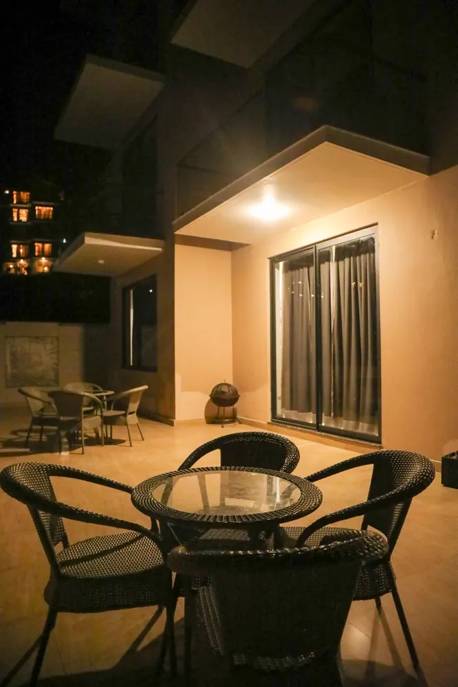 Terrace at night with a round glass table and wicker chairs in front of sliding glass doors
