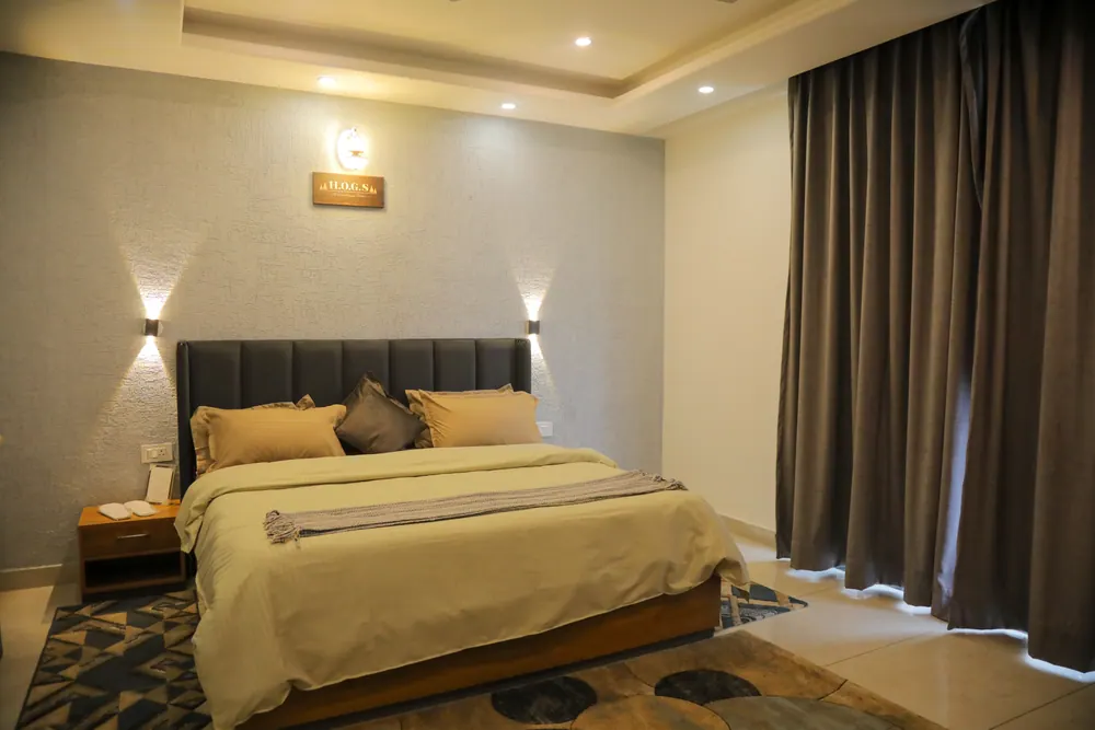 Bedroom with a double bed, a grey padded headboard, two wall lamps and heavy curtains