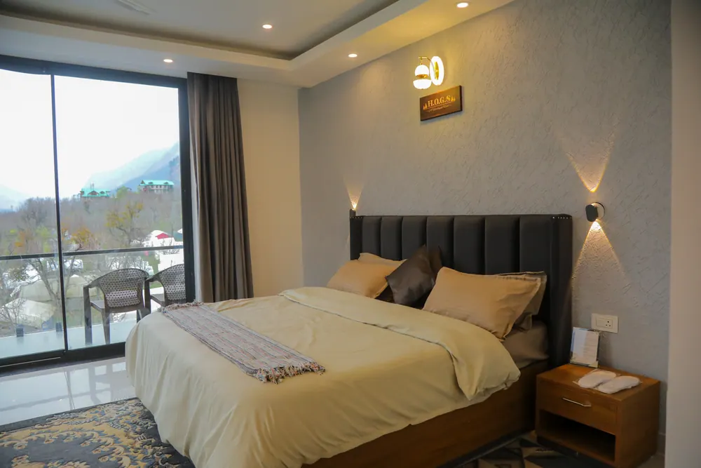 Bedroom with a double bed, wall lights and a glass door leading to a balcony with chairs
