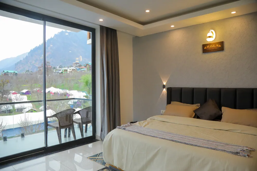Bedroom with a sliding glass door to a balcony with chairs and a view of the mountainside